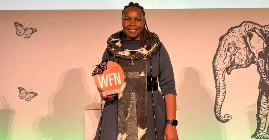 Dr Moreangels Mbizah on stage holding the 2026 Whitley Award trophy