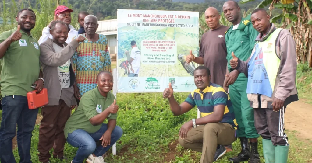 Local community members, forest guards, and Herp-Cameroon team gathered around a Mount Manengouba Protected Area signboard.