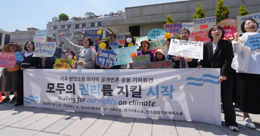 South Korean youth plaintiffs holding Ruling for our rights on climate banner outside Constitutional Court