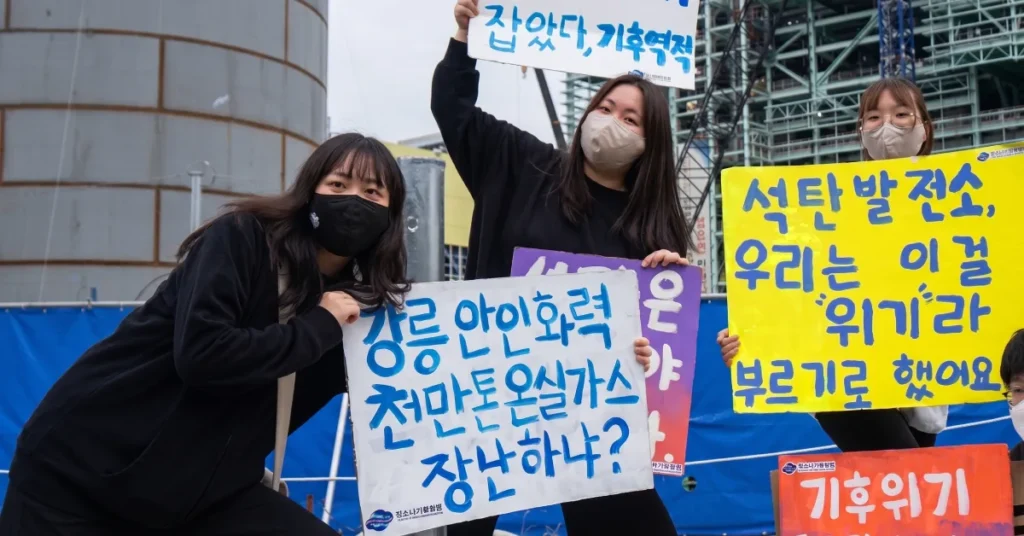 Youth 4 Climate Action activists holding protest signs against coal power plant emissions in South Korea