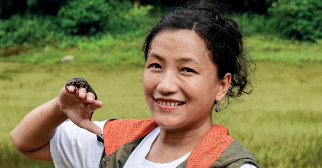 Dr Barkha Subba smiling while holding a vulnerable Himalayan salamander during wetland conservation in Darjeeling